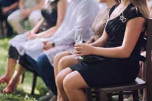 Woman wearing black holding glass of champagne during wedding ceremony