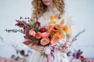 Bride holding a large wedding bouquet with orange, red, and pink flowers