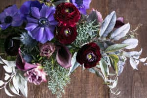floral design, wedding decor, love concept. top view of adorable bouquet of different flowers, there are delicate pink roses, lilac anemones and dark maroon persian buttercups